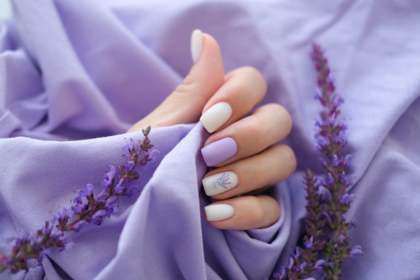 Women's hands with trendy very peri manicure and flowers in purple/ envato/ smile23